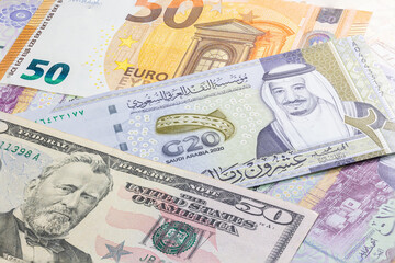 Close up 20 Riyals of Saudi Arabia between 50 US Dollar and 50 Euro banknotes. Twenty Riyal banknotes of the Arabic country. Money of the US and Europe with Saudi Riyal banknote. G20 summit banknote