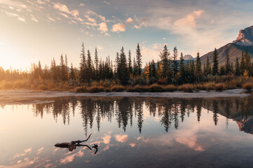Sunrise on Rocky mountains and autumn forest reflection on the river at national park