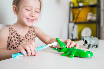 happy little child brushes his teeth with toy. fun game as aid in oral care. dental hygiene with...