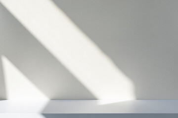 Sunlight and abstract shadows on the wall and white desk. Silhouette of lines on blank surface, mockup, space for text.