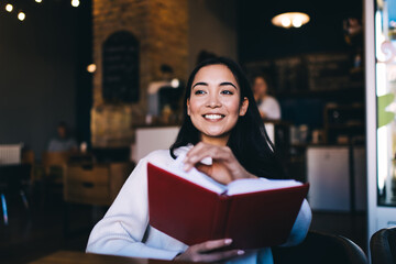 Cheerful woman with book in cafe