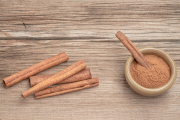 dried cinnamon sticks and powder on wooden table with copy space