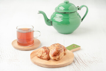 homemade pastry buns, glass of tea and teapot on the table