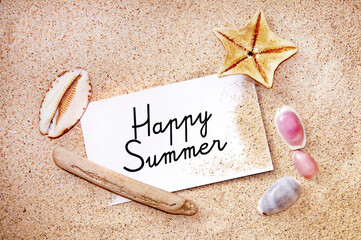 Happy summer written on a note on white beach sand, starfish and shells