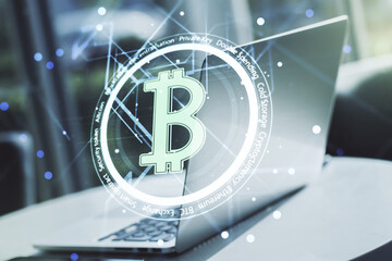 Double exposure of creative Bitcoin symbol with modern laptop on background. Cryptocurrency concept