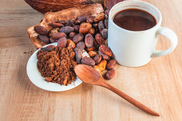 Hot cocoa cup with cocoa powder and cocoa beans on wooden background