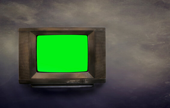 Old television set with green screen for adding new images onto the screen with vintage dark background.