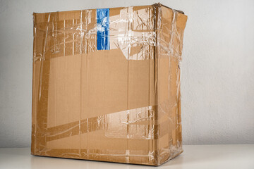Old cardboard box partially wrapped with tape. Blue and transparent tape on the box. Old cardboard...