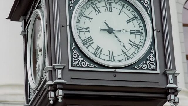 Beautiful clock tower outdoors in the city street. Video. Concept of vintage architecture, ancient clock tower with roman numerals.