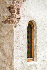 Architectural elements of the wall, windows with colored stained glass. An old wall with cracks.