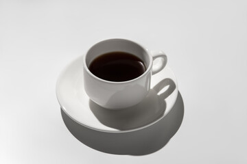 white coffee cup with espresso. hard shadows on gray background