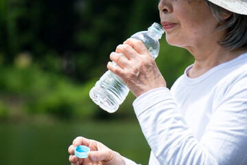 The elderly person who drinks water in nature. 自然の中で水分補給をする高齢者