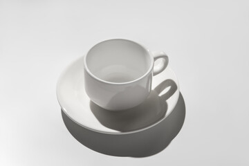 empty white coffee cup. hard shadows on gray background