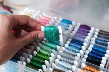 Close up of colorful embroidery floss bobbins in the box. Embroidery threads for handmade, crafts,...