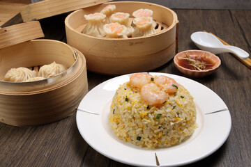 Prawn shrimp shaomai Xiao long bao dim sum dumpling chicken prawn fish seafood vegetable in bamboo steamer fried rice on plate sauce chopsticks soup spoon over rustic background