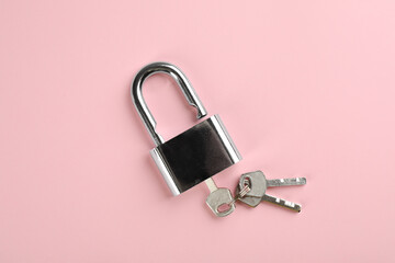 Modern padlock with keys on pink background, top view