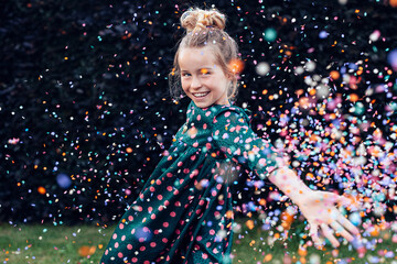 beautiful smiling little girl under a shower of confetti - birthday party carefree celebration concept - obrazy, fototapety, plakaty