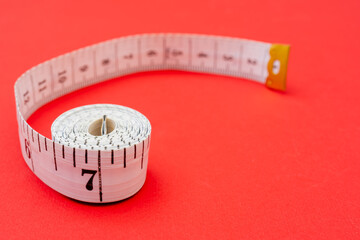 White measuring tape on red background. Measurement of length and circumference. Lose weight and...