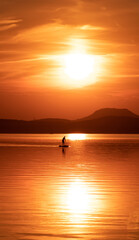 landscape with a man paddling on the lake in the evening