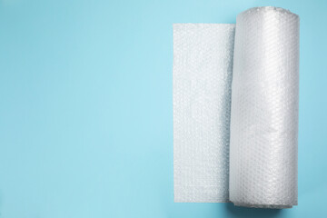 Bubble wrap roll on turquoise background, top view. Space for text
