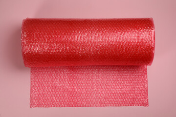 Bubble wrap roll on light pink background, top view