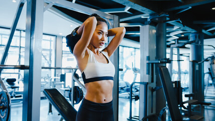 Beautiful young Asia lady exercise doing lifting barbell fat burning workout in fitness class. Athlete with six pack, Sportswoman recreational activity, functional training, healthy lifestyle concept.