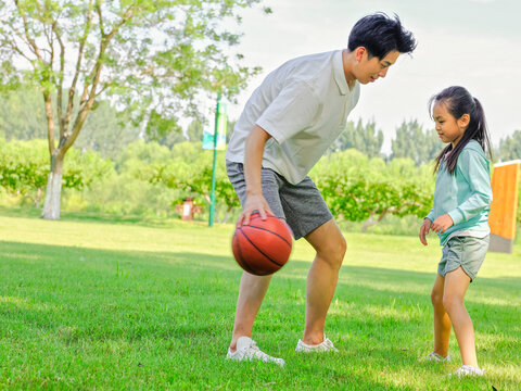 Happy father and daughter are playing basketball in the park