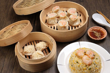 Prawn shrimp shaomai Xiao long bao dim sum dumpling chicken prawn fish seafood vegetable in bamboo steamer fried rice on plate sauce chopsticks soup spoon over rustic background