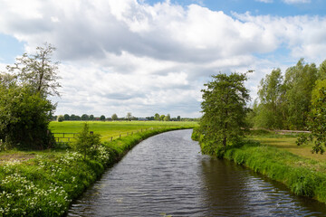 Fototapeta na wymiar The river, called De Barneveldse beek, flows gently through the flat farm landscape.