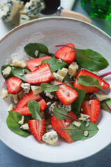 Close-up of salad with fresh strawberries, mangold leaves and blue cheese, vertical shot, selective focus