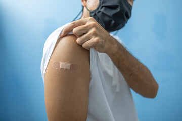 Young man show plaster on arm after vaccination against COVID-19 infection, Young man vaccinated against coronavirus infection. 