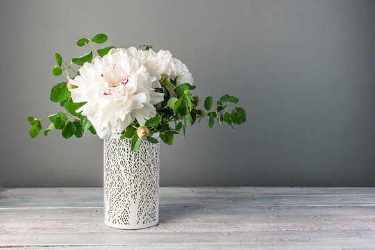 Flower arrangement with white peonies flowers in a vase on a grey background