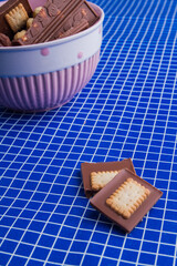 Chocolate bar pieces and bowl on a blue checkered background.
