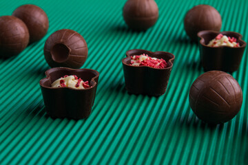 Close-up brown sweet chocolate candies on green background.