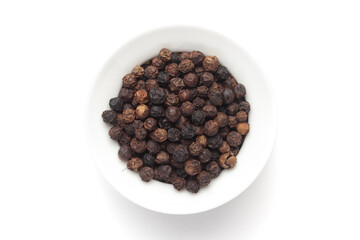 Macro close-up of Organic Black pepper (Piper nigrum) on white background. Pile of Indian Aromatic Spice. Top view