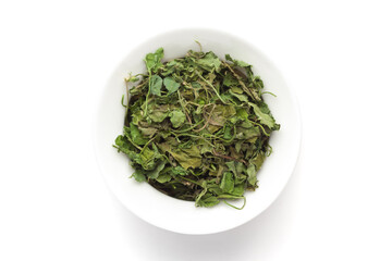 Macro close-up of Organic green dry Fenugreek leaves (Trigonella foenum-graecum) on white background. Pile of Indian Aromatic Spice. Top view