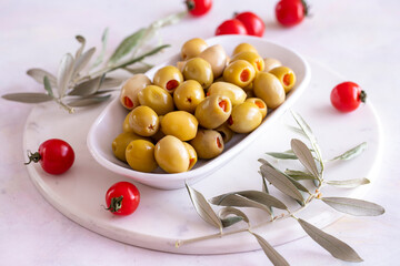 Green olives stuffed with peppers. Tasty organic green olives in the plate. Olive on marble floor