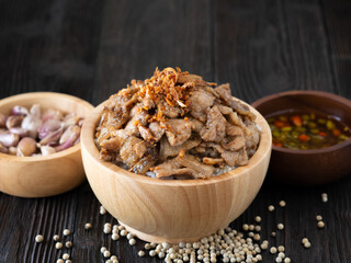 Thai food, Rice topped with pork and garlice in wooden bowl on brown wooden table. Favorite food in Thailand.