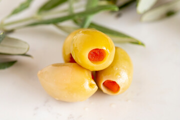 Close-up of green olives with pepper filling. Organic green olives on a marble floor
