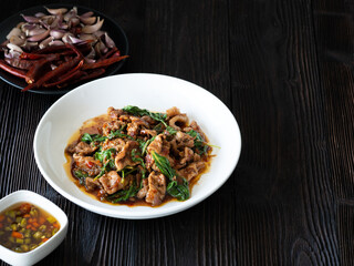 Thai food, Stir fried pork and basil in white plate on brown wooden table. Favorite food in Thailand.