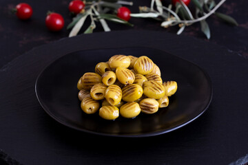 Grilled green olives on a dark background. Tasty Green grilled olives in the bowl