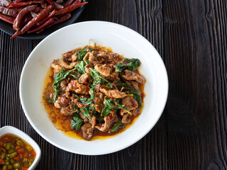 Thai food, Stir fried pork and basil in white plate on brown wooden table. Favorite food in Thailand.