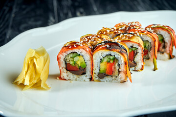 Veggie sushi roll of vegetables, carrots, tomato, cucumber and avocado, served in a white plate on a black background. Japanese cuisine