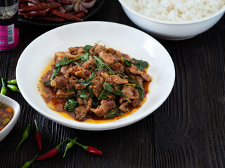 Thai food, Stir fried pork and basil in white plate on brown wooden table. Favorite food in Thailand.
