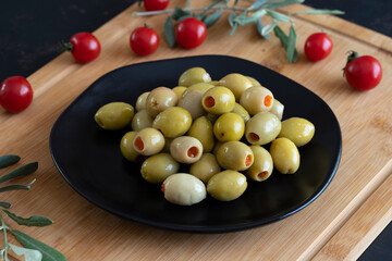Green olives stuffed with peppers on a dark background. Tasty green olives in the plate.