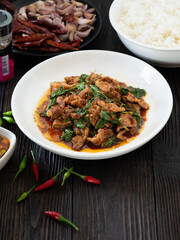 Thai food, Stir fried pork and basil in white plate on brown wooden table. Favorite food in Thailand.