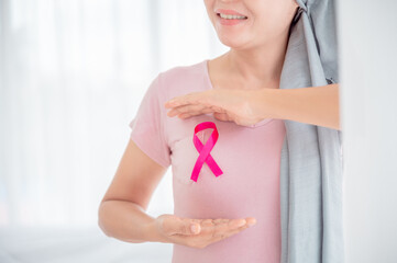 Asian women attach a pink ribbon to their tops. Doing exercise by lifting pink dumbbells on color...