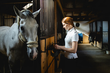 Portrait of a girl preparing her horse for riding.