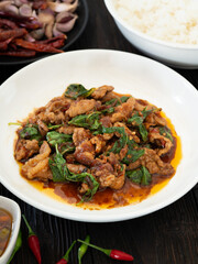 Thai food, Stir fried pork and basil in white plate on brown wooden table. Favorite food in Thailand.
