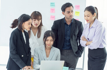 A group of young men and women brainstorm on discussion planning while doing a team workshop together in a company meeting room. 